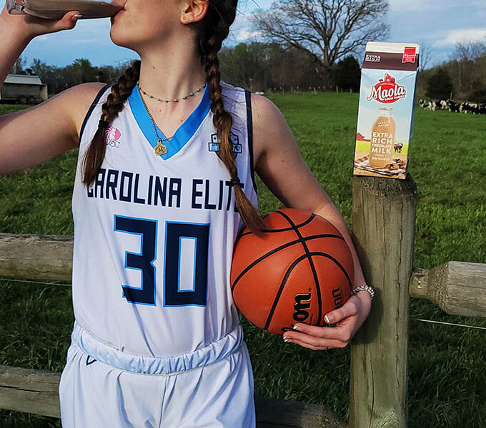 Athlete drinking chocolate Maola milk and holding a basketball while on a farm
